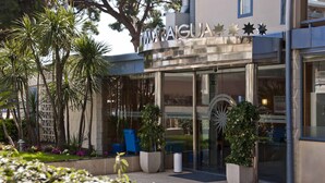 A modern building with a glass entrance, outdoor seating, and potted plants. - Hotel Amaraigua - Adults Only (Malgrat de Mar)