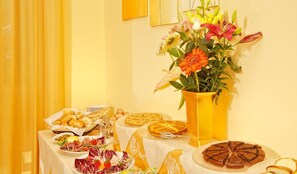 A table with various food items and a large vase of flowers. - Jonic Hotel Mazzaro' (Taormina)