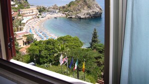 Une vue sur la côte, avec une plage, des parasols et des drapeaux.