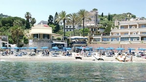 Un hôtel situé sur la côte, doté de nombreux balcons, d’un espace de détente au bord de la plage et offrant une vue sur la mer.