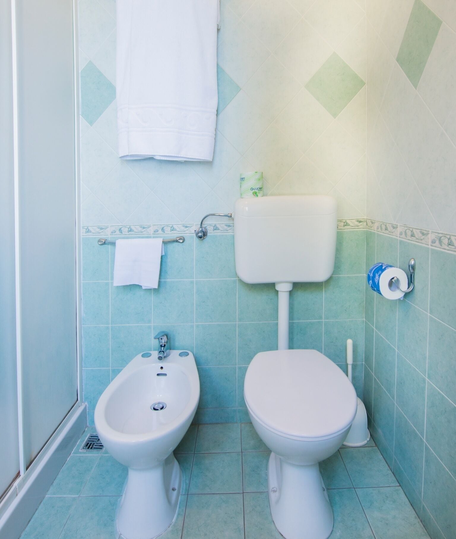A bathroom with a bidet, toilet, and a towel rack.