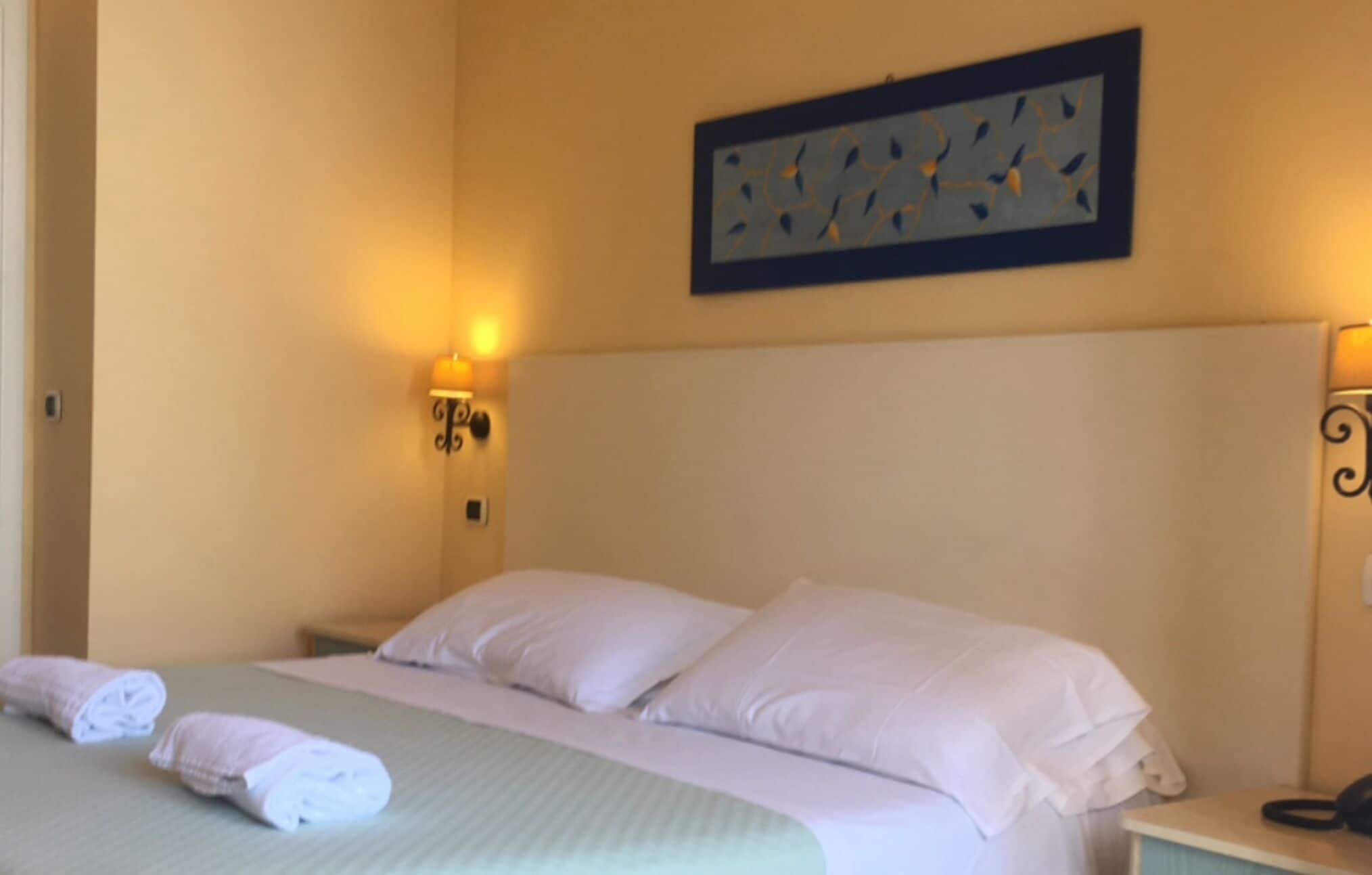 Ein Hotelzimmer mit Bett, zwei Kissen, Kopfteil und einem Wandbild.