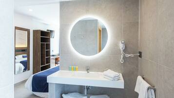 Un baño moderno con un espejo redondo, un lavabo blanco y un perchero para toallas.