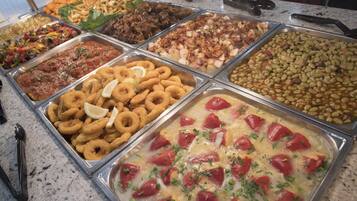 Un bufé con diversas opciones de comida, incluyendo frituras, ensaladas y un plato de pasta.