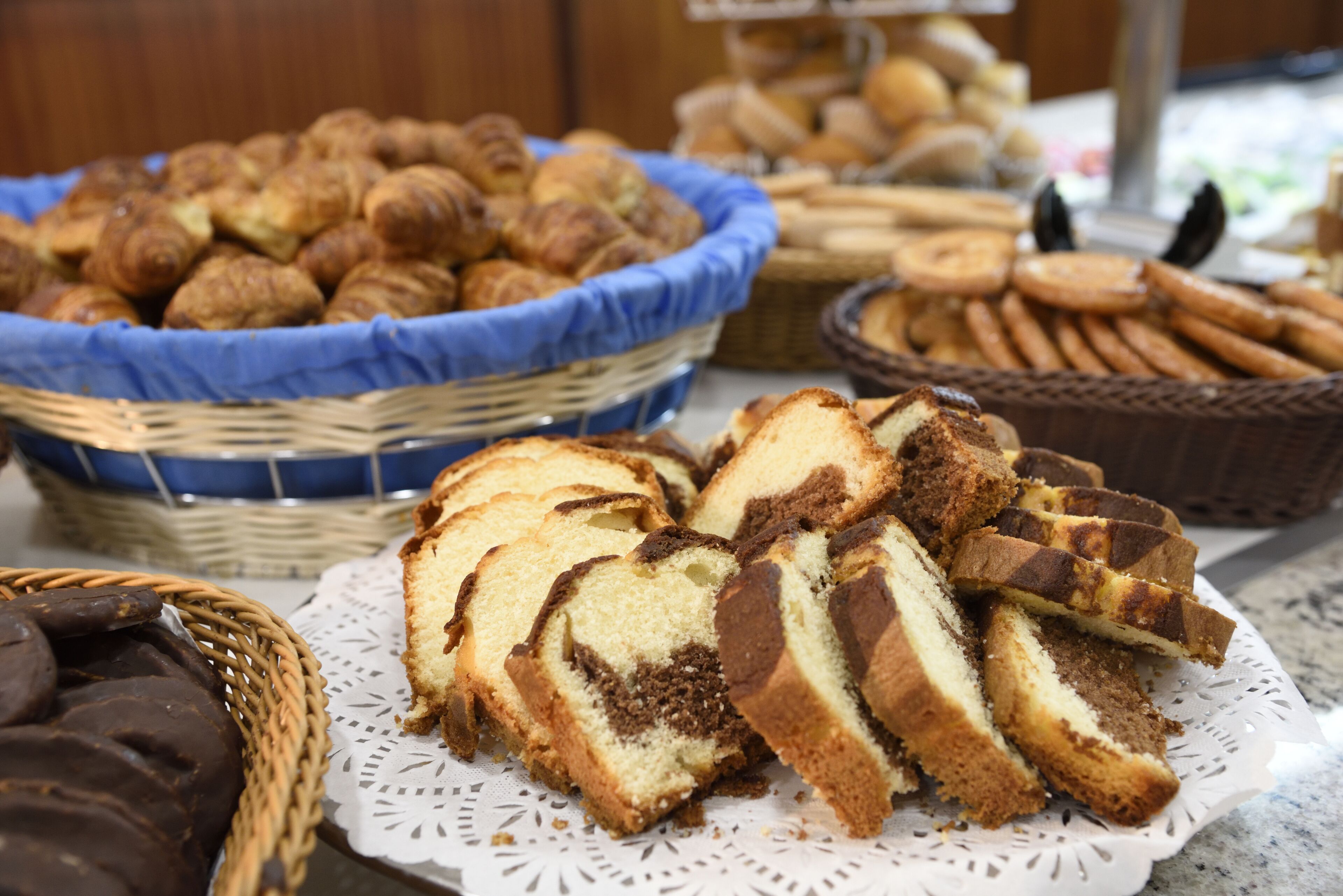 Diverse gebakken producten, zoals brood, gebak en koekjes, op een tafel uitgestald.