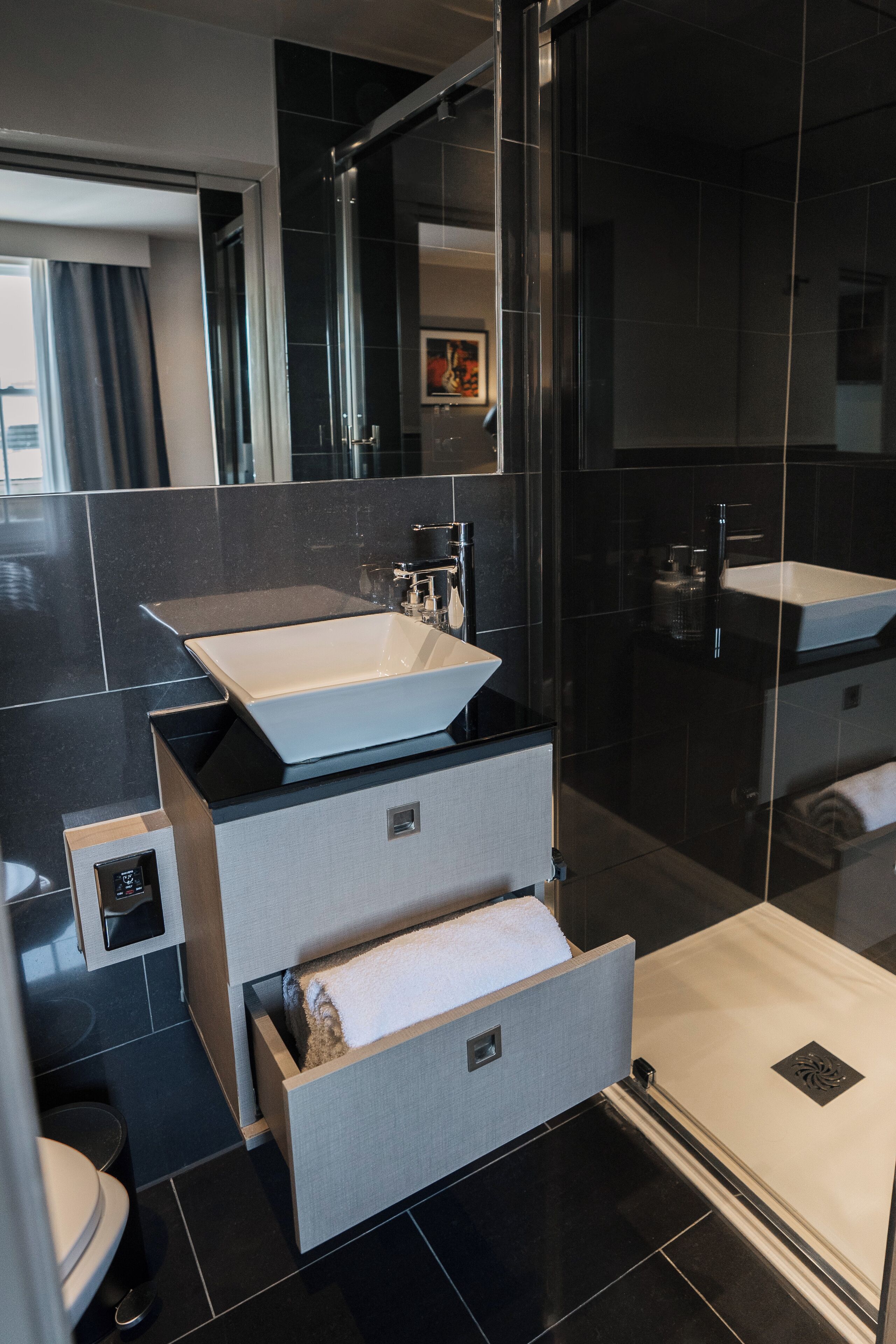 A modern bathroom with a large sink, a mirror, and a shower.