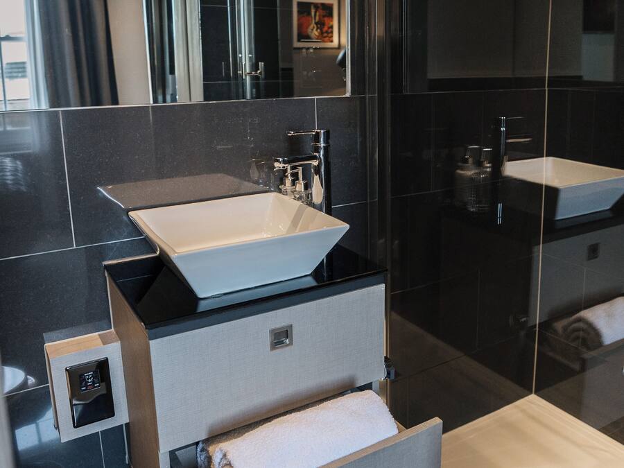 A modern bathroom with a large sink, a mirror, and a shower.