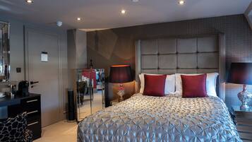 A modern bedroom with a large bed, a dresser, a mirror, and a desk.