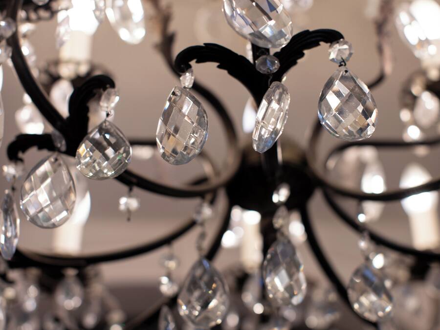 Um candelabro com diversos elementos de cristal e braços de metal preto.