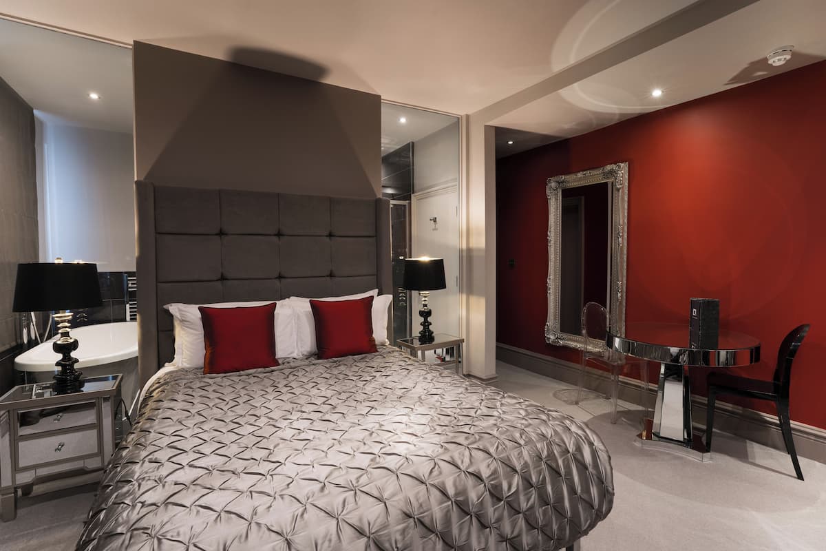 A modern bedroom with a large bed, a vanity, and a mirror.