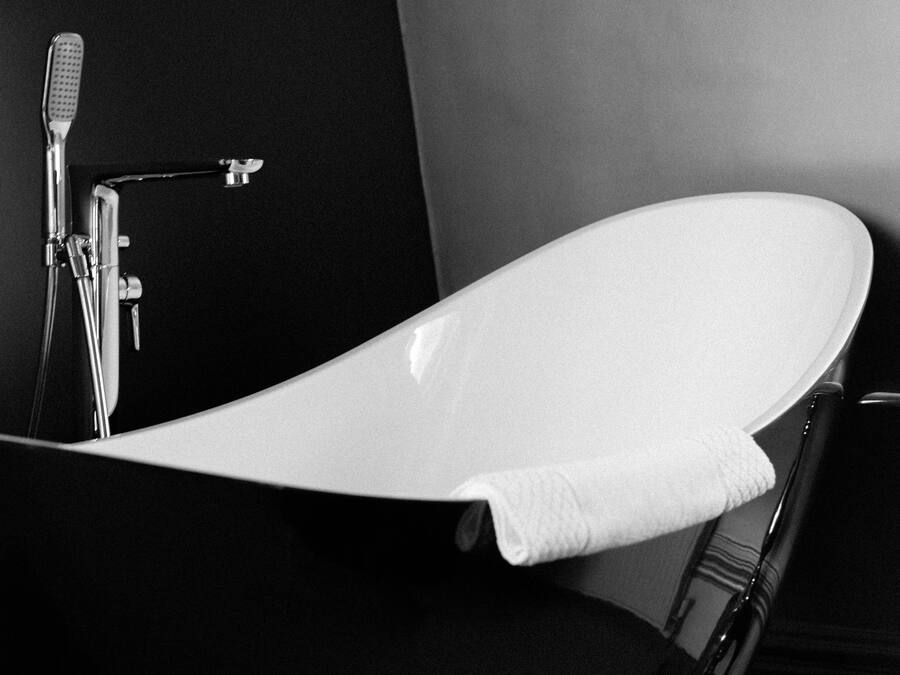 A modern bathroom with a freestanding bathtub, a handheld showerhead, and a towel hanging on the side.