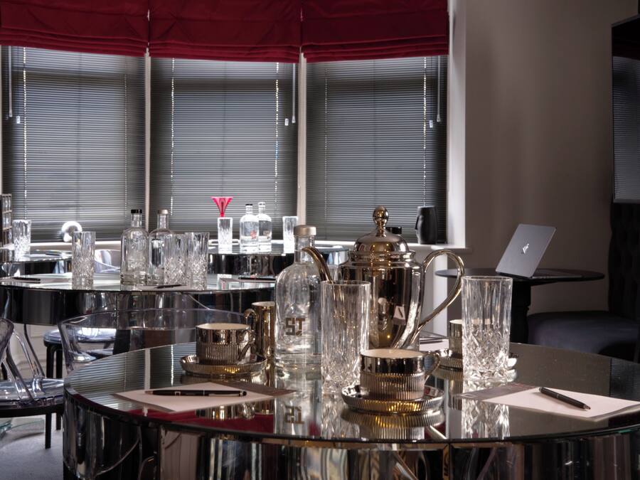 Une salle de conférence moderne, dotée de tables en verre, de beaux verres et d’un ordinateur portable posé sur l’une des tables.
