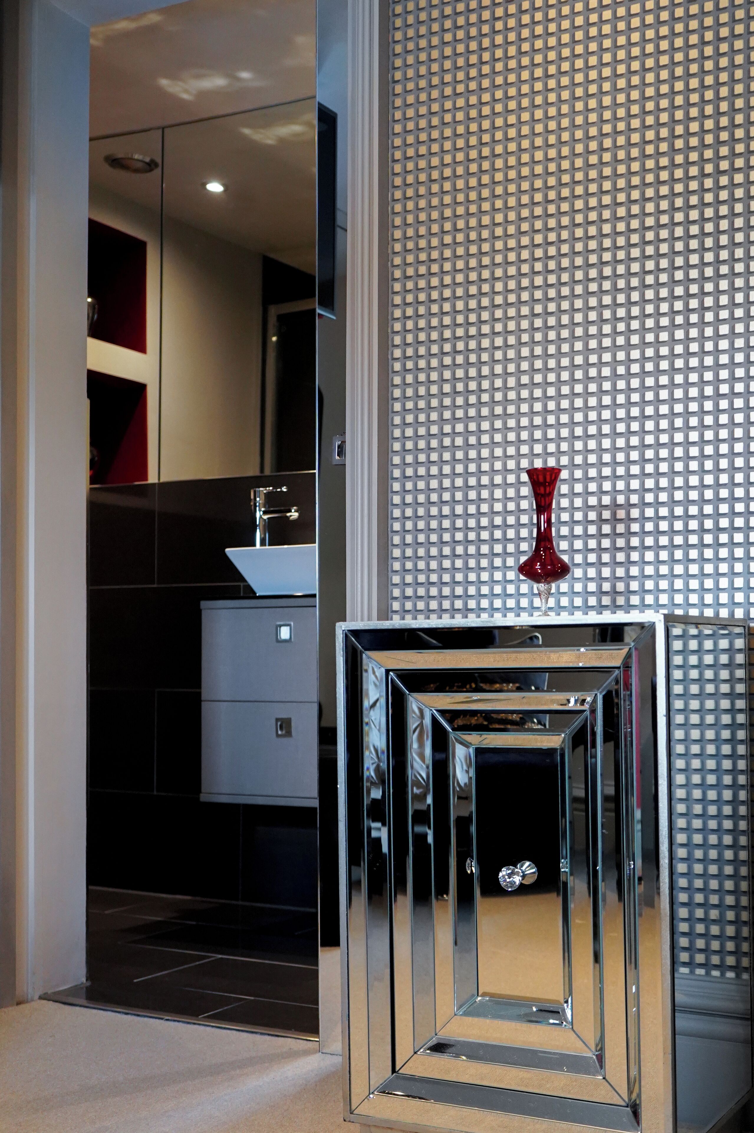 Une salle de bain moderne avec un grand miroir, un lavabo et un vase décoratif.