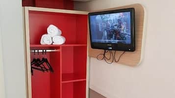 A room with a red wardrobe, a mounted TV, and an air conditioning unit.