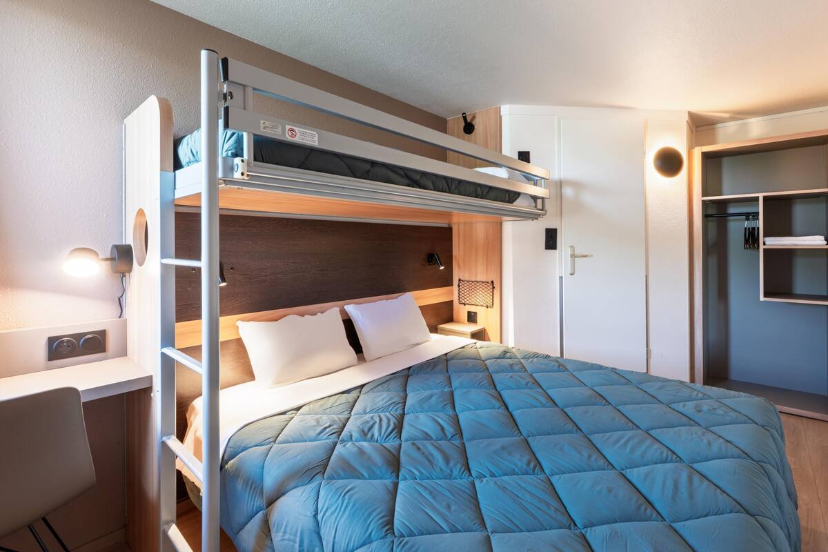 A bunk bed with a desk and a wardrobe.