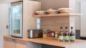 Une cuisine équipée d’un réfrigérateur, d’un grille-pain, de paniers en osier et de distributeurs d’assaisonnements.