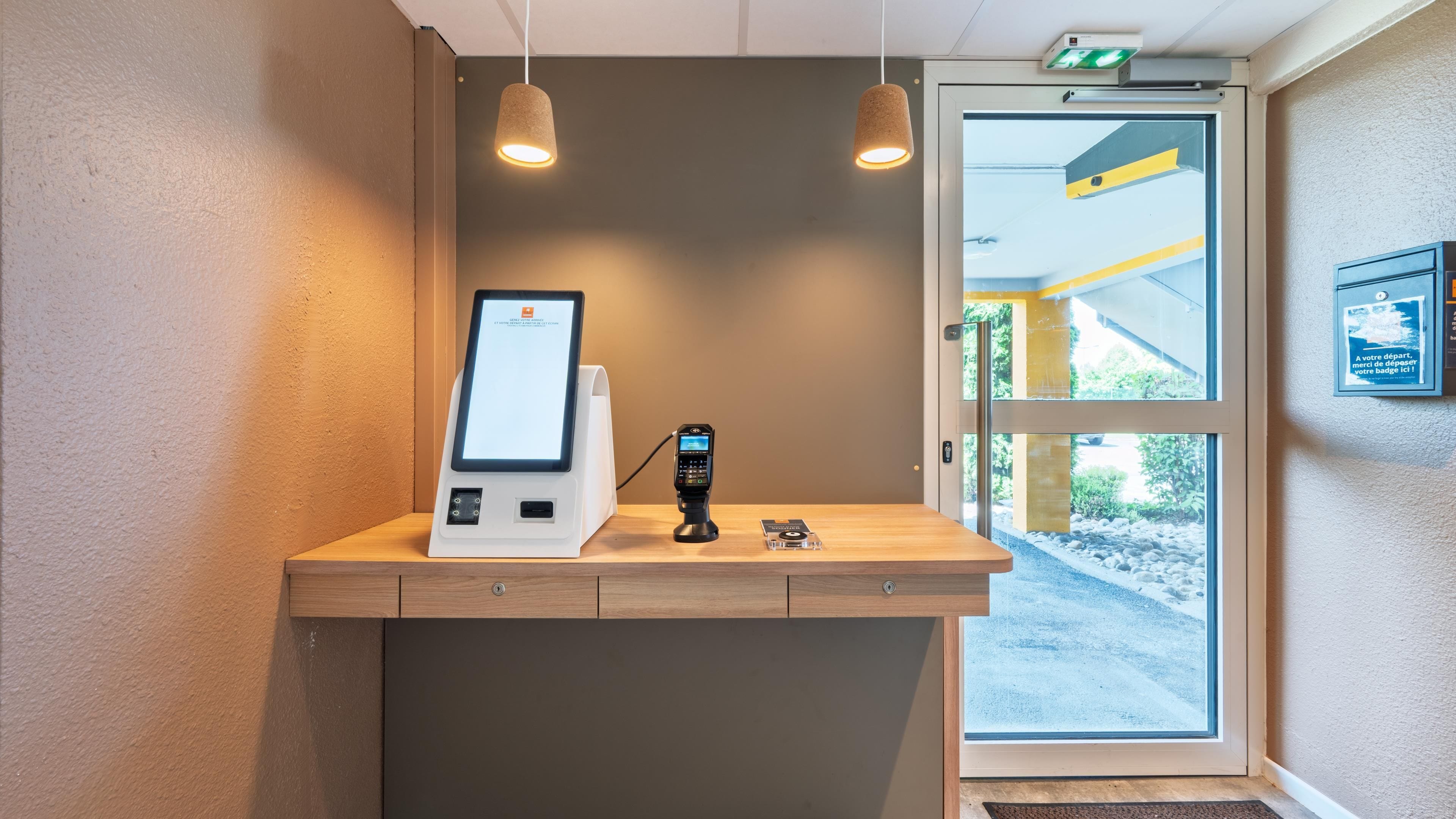Un chiosco self-service con lettore di carte, un piccolo schermo e una stazione di ricarica.