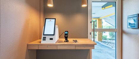 Un chiosco self-service con lettore di carte, un piccolo schermo e una stazione di ricarica.