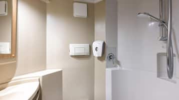 A bathroom with a shower, a hand dryer, and a soap dispenser.