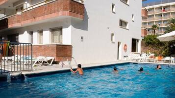 Een seizoensgebonden buitenzwembad, ligstoelen bij het zwembad