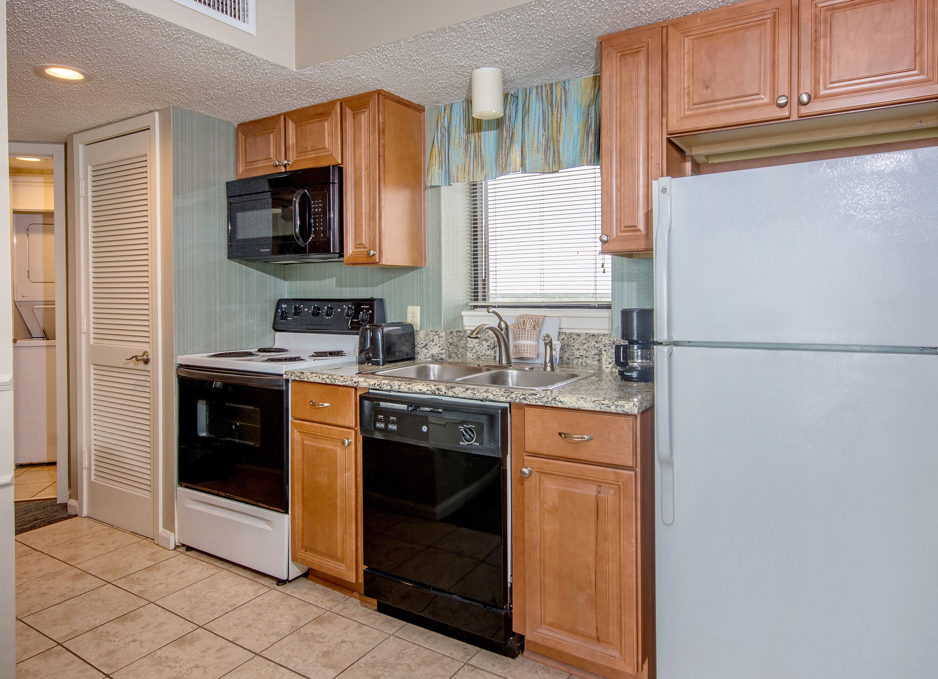 A compact kitchen with a stove, microwave, dishwasher, and refrigerator.