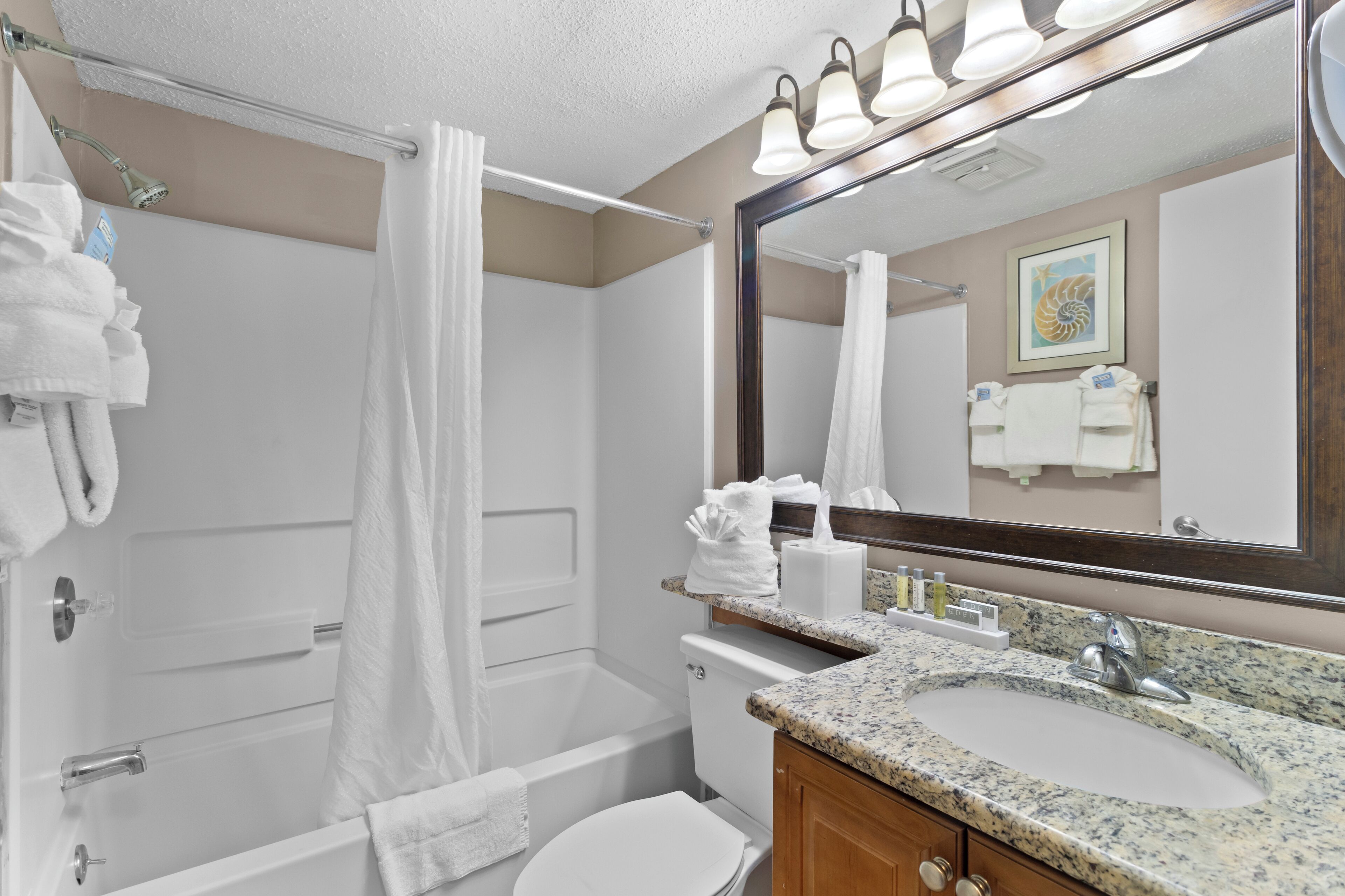 A bathroom with a sink, mirror, shower, and toilet.