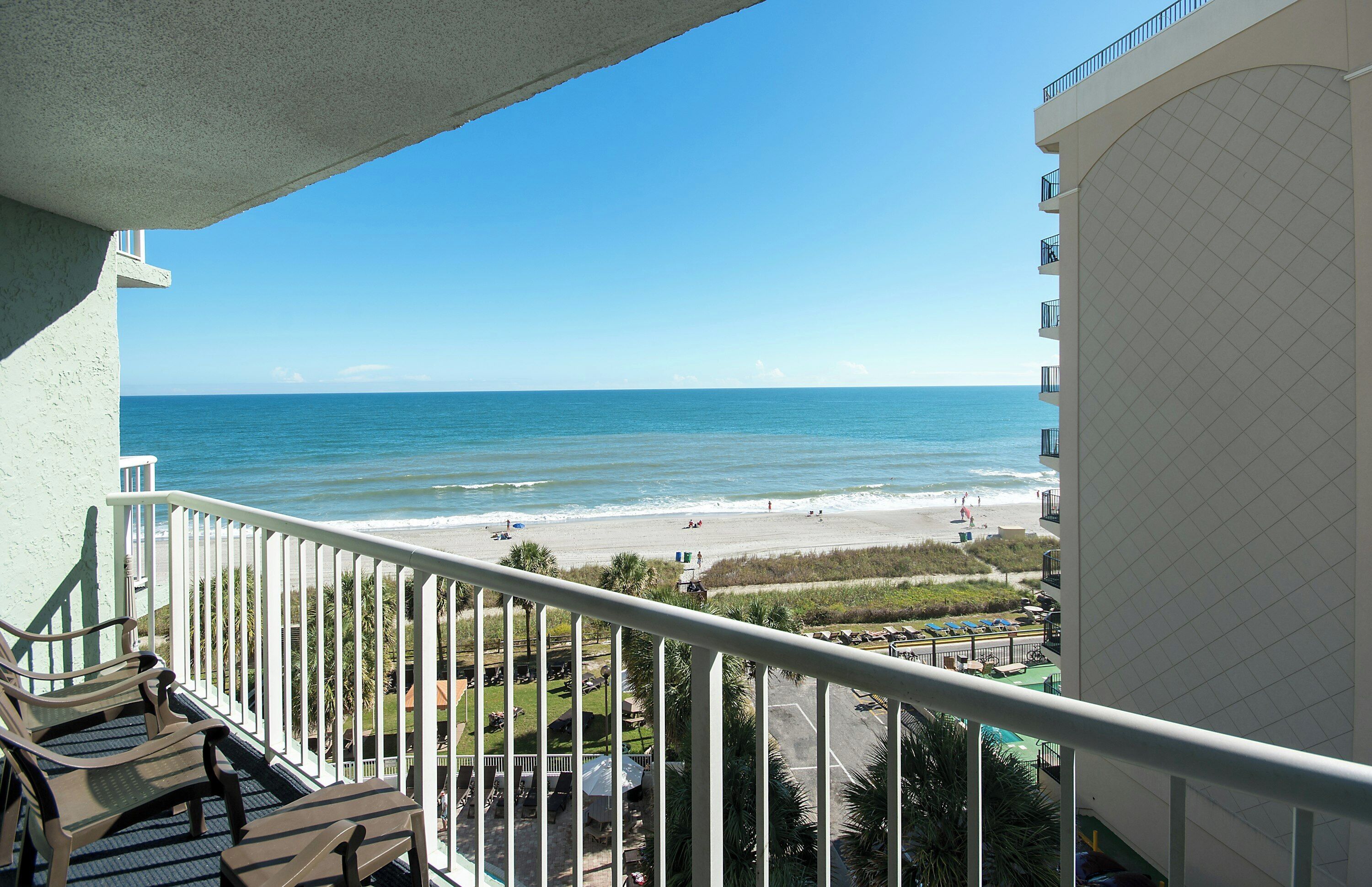 A balcony with a view of the beach and ocean.