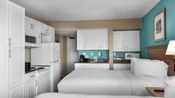 Habitación de hotel con kitchenette, dos camas, baño y vistas a la ciudad.
