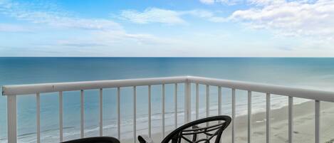 A balcony with a view of the beach and ocean.