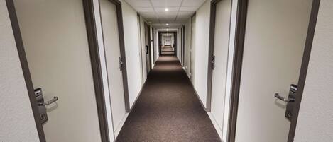 A long, narrow hallway with doors on both sides, leading to individual rooms.