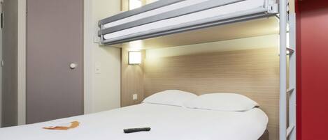 Una cama individual con cabecera, mesita de noche y lámpara de pared.