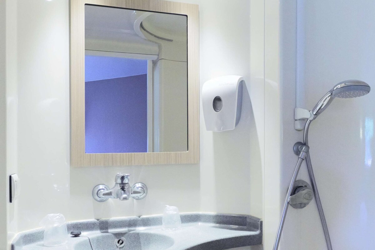 Un baño moderno con lavabo, espejo y ducha.