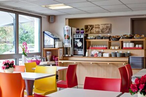 A restaurant with a counter, seating area, and various food and drink items. - Hotel Première Classe Chalon Sur Saone (Chalon-sur-Saone)