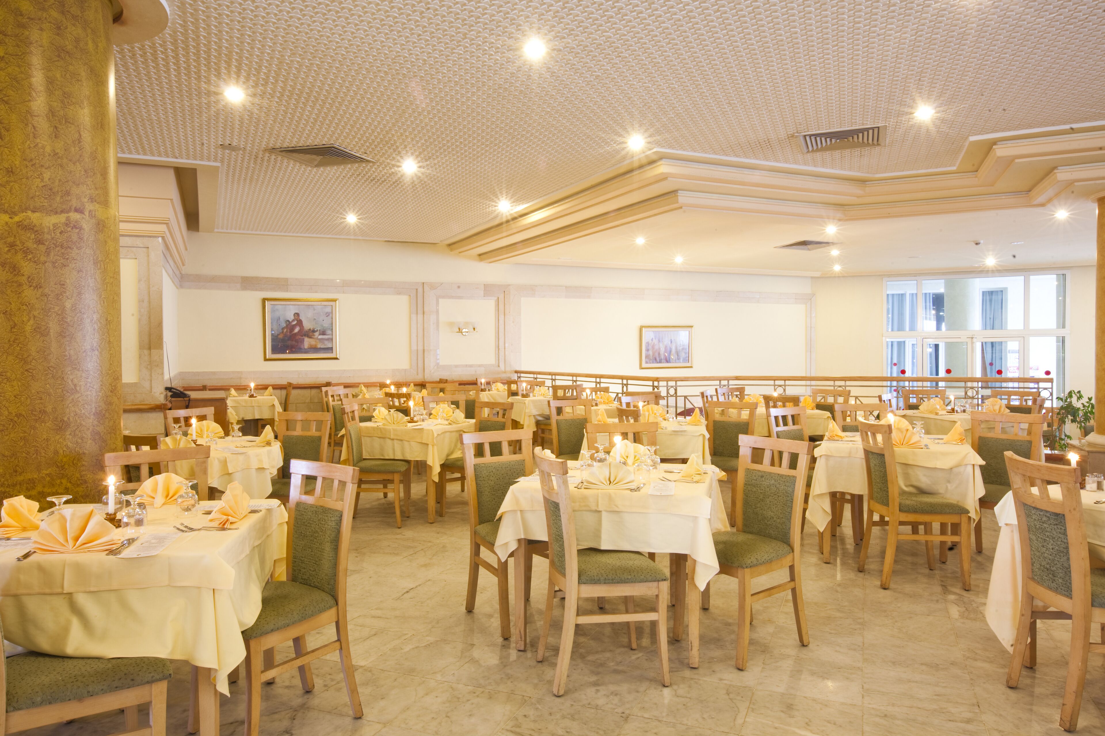 A spacious dining hall with multiple tables and chairs, arranged in rows.