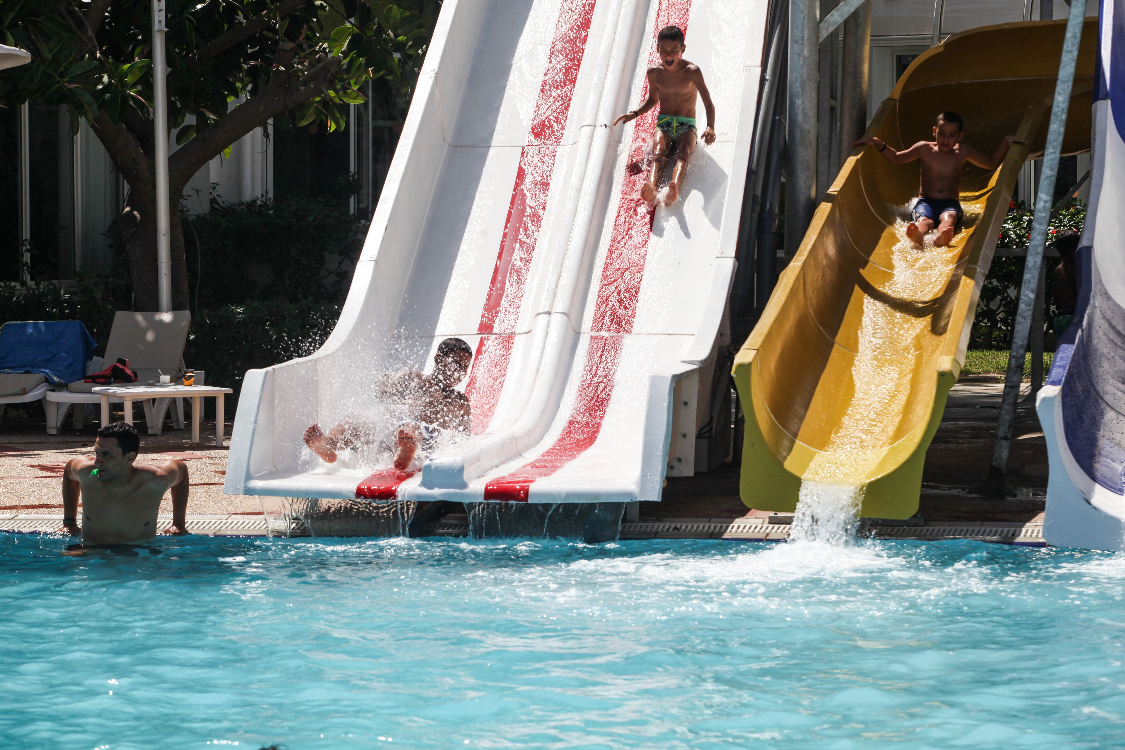 A pool with two slides, one red and white and one yellow.