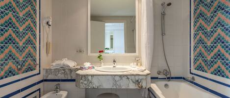 A bathroom with a sink, bidet, and bathtub.