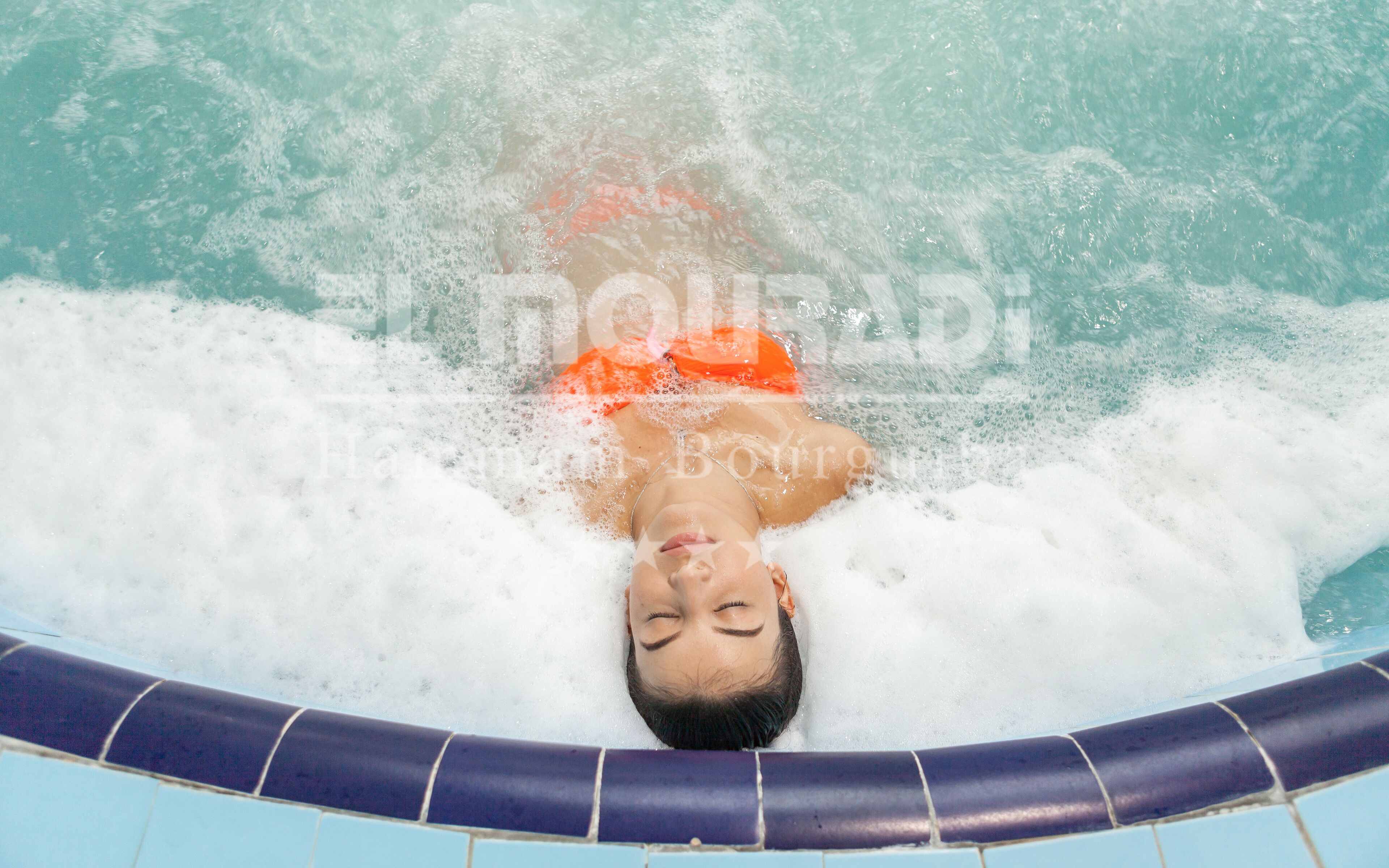 A person in a hot tub with visible bubbles and water.
