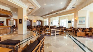 Eine großzügige Lobby mit einer Rezeption, mehreren Sitzbereichen und einem polierten Marmorboden.