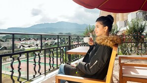 Ein Balkon mit Blick auf einen Tennisplatz und Berge.