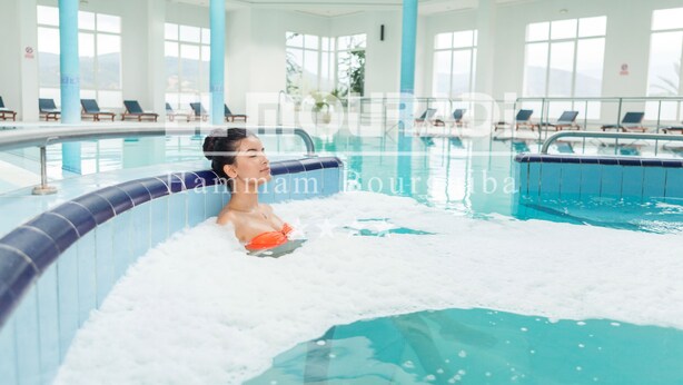 Ein Poolbereich mit Liegestühlen und einer Person in einem Whirlpool.