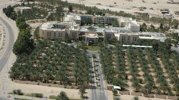 An aerial view of a large, multi-story building with a central courtyard surrounded by palm trees.
