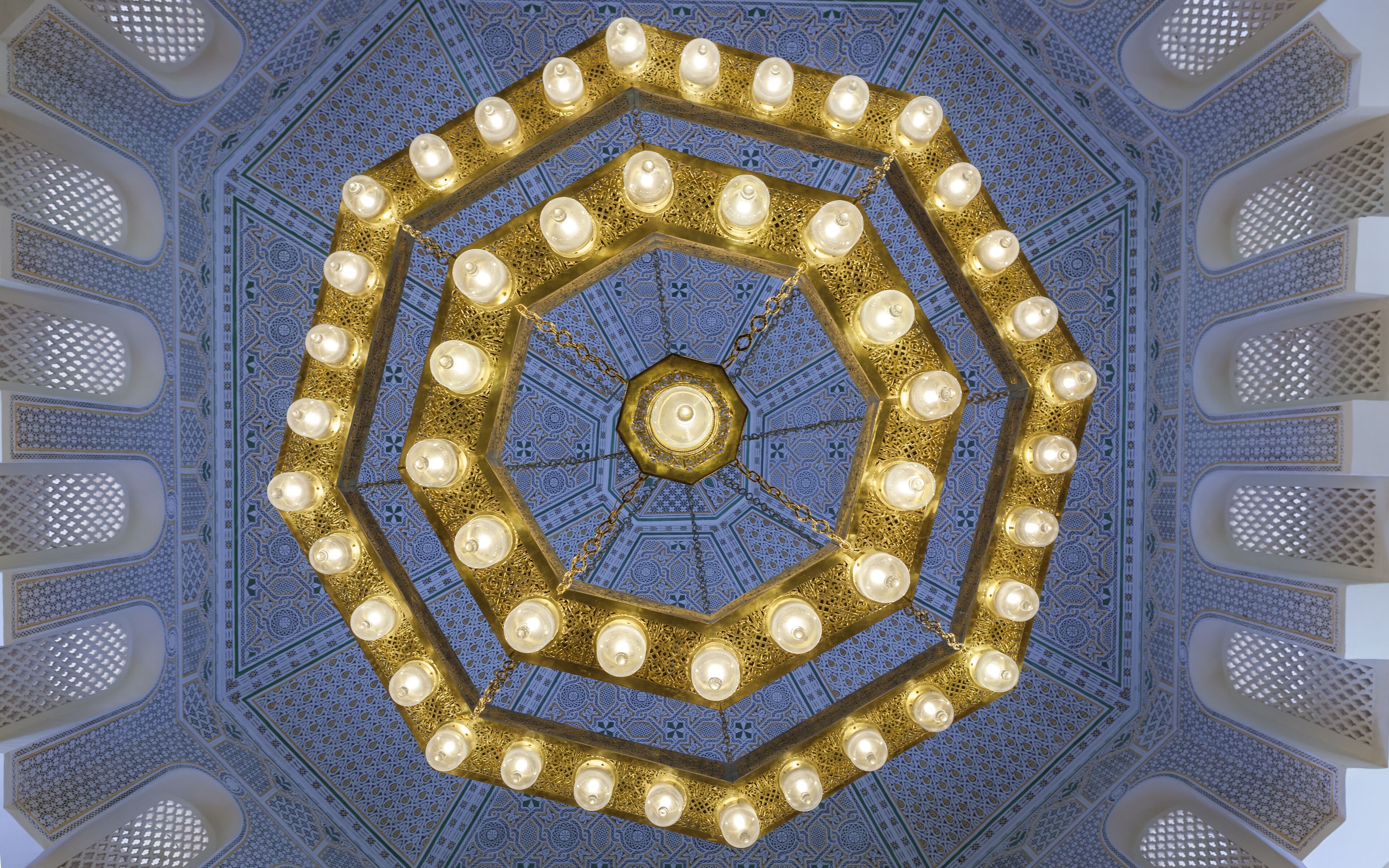 A detailed view of a ceiling with a geometric pattern and multiple light fixtures.
