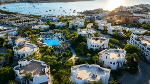 A coastal resort with a central swimming pool, multiple villas, and a marina with boats.