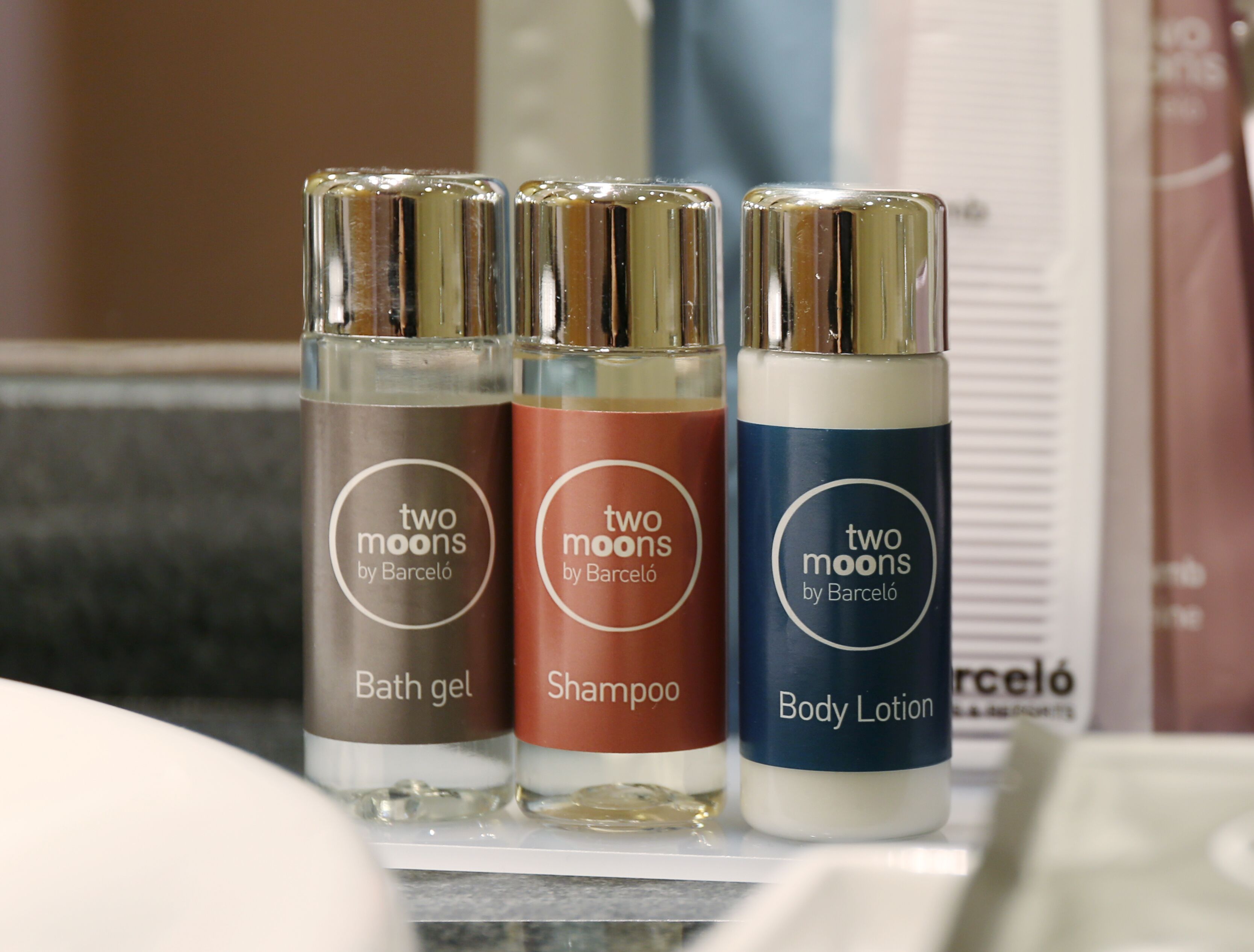 Three bottles of 'two moons by Barceló' products: bath gel, shampoo, and body lotion.