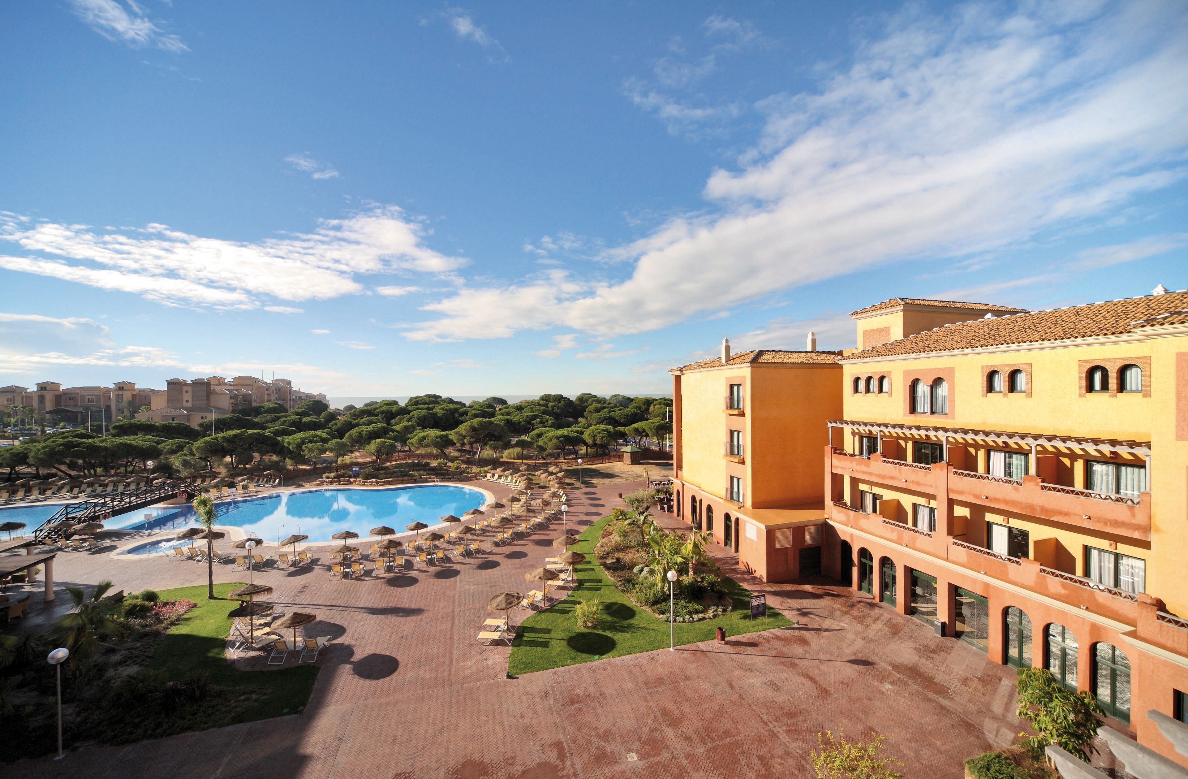 A hotel with a swimming pool, outdoor seating, and a courtyard.