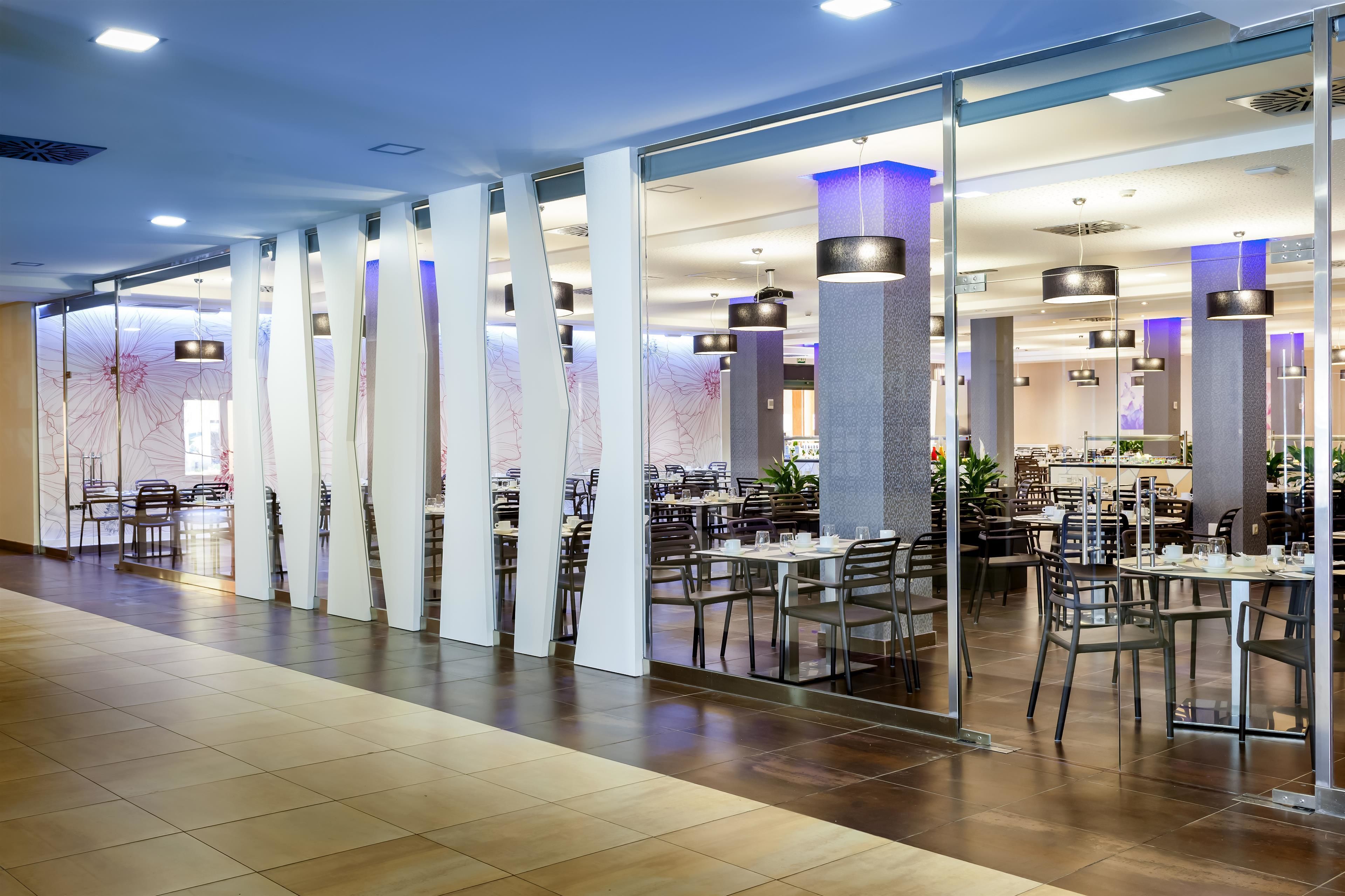 Un ristorante spazioso con tavoli e sedie alti, ampie colonne e lampade moderne.