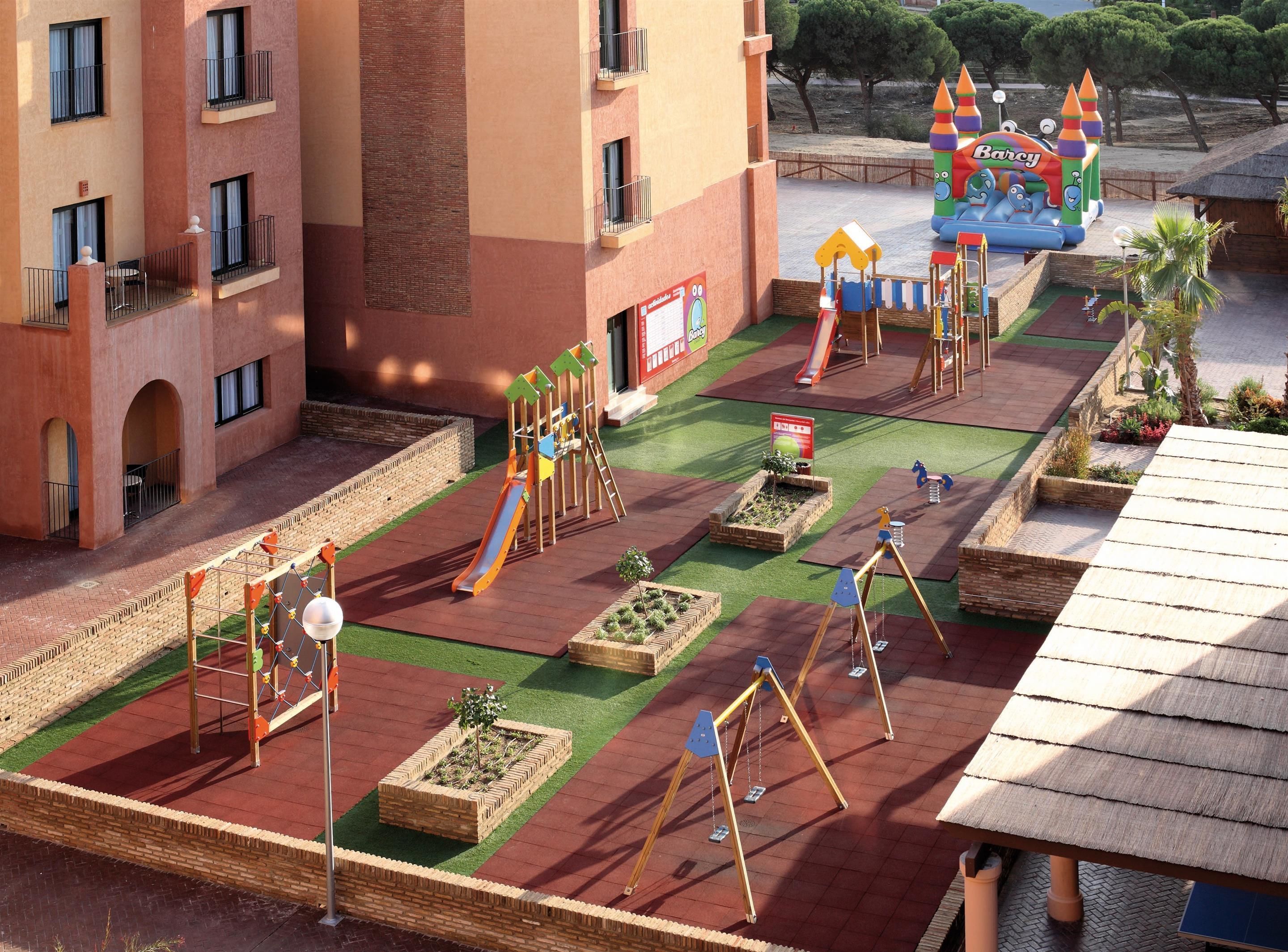 Un área de juegos infantiles con tobogán, columpios y una estructura para escalar.