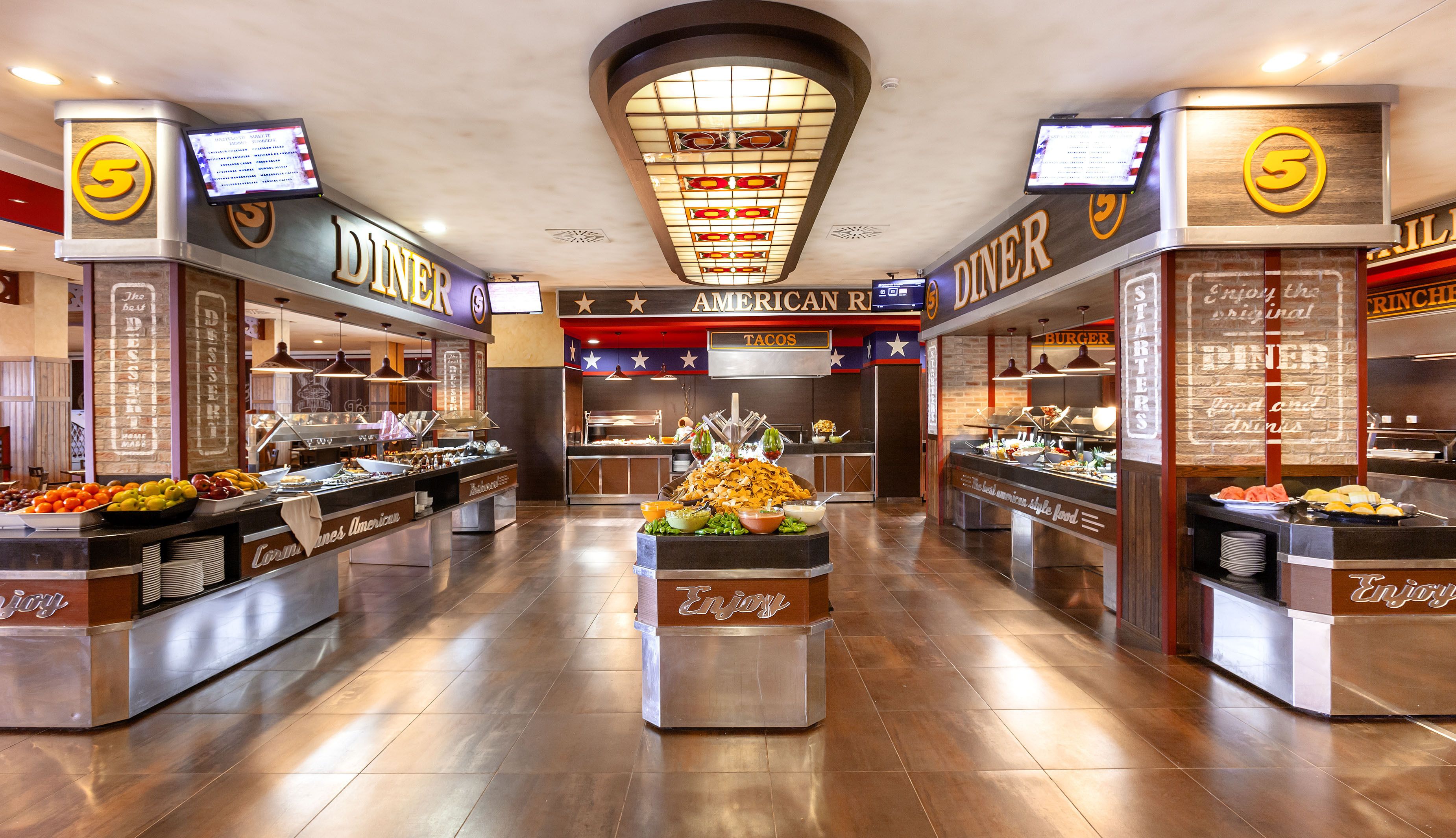 A diner with multiple food stations, including a taco and burger area, and a dessert section.
