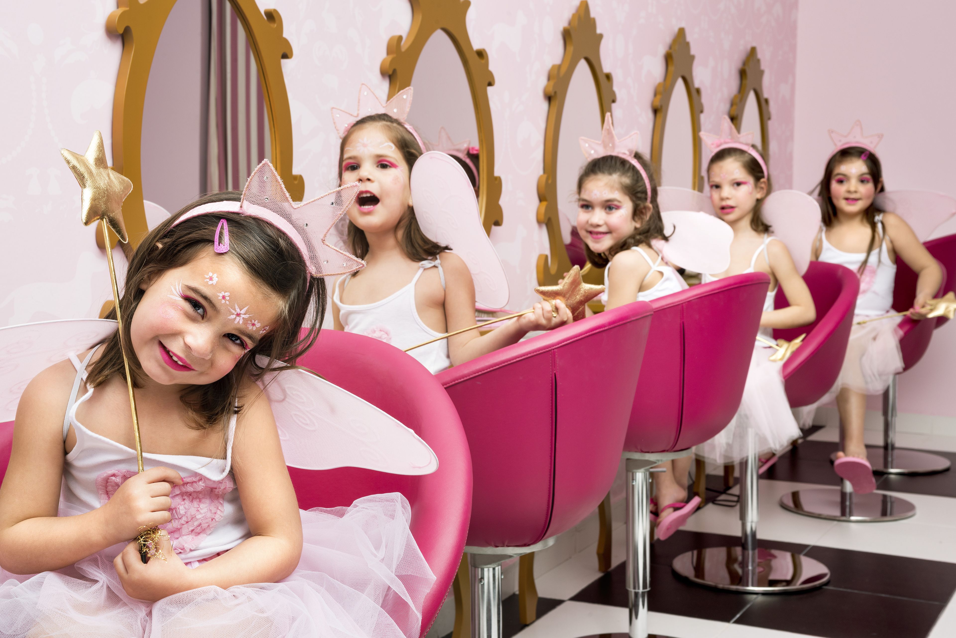 Un salón con sillas rosadas y espejos.