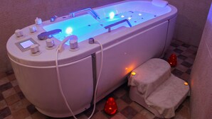A modern bathroom with a large bathtub, a control panel, and a small stool. - Rodes (Djerba Midun)